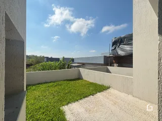 Vista do quintal com gramado e muro de concreto.
