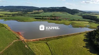 Vista aérea de uma paisagem rural com um lago cercado por campos verdes.