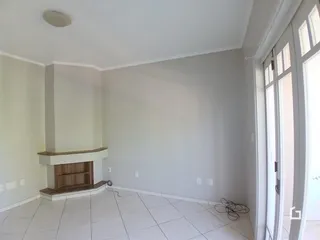 Ambiente interno de uma sala com piso de cerâmica e lareira em tom de madeira.