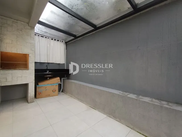 Vista interna de um espaço com teto de concreto aparente e piso de cerâmica.