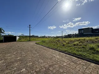 Vista externa de uma propriedade com paisagismo e acesso pavimentado.