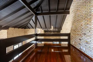 Foto de um ambiente interno com piso de madeira e estrutura de vigas expostas.