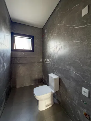 Foto de um banheiro com paredes de mármore cinza e um vaso sanitário branco.