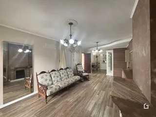 Sala de estar com piso de madeira e sofás decorativos.