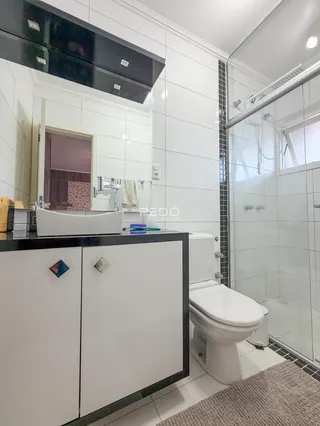 Banheiro moderno com revestimento branco e box de vidro.