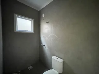 Foto de um banheiro com paredes cinzas e uma janela.