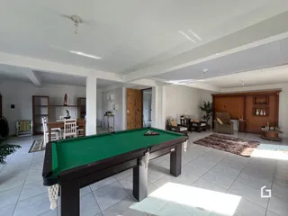 Ambiente interno de uma sala com mesa de bilhar em um imóvel.