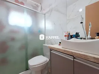 Banheiro com box de vidro e bancada clara.