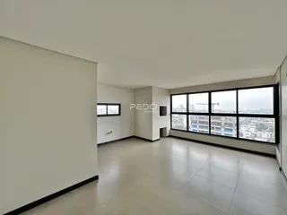 Ambiente interno de uma sala ampla com vista para a cidade.