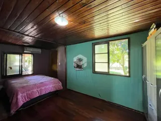 Quarto com piso de madeira e teto de madeira em uma residência.