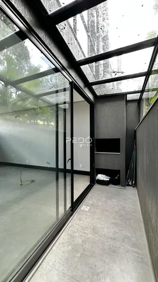 Interior de um espaço moderno com grandes janelas de vidro e piso de concreto.