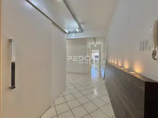 Corredor interno de uma residência com piso de cerâmica clara.