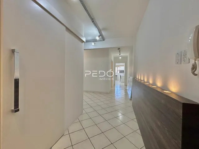 Corredor interno de uma residência com piso de cerâmica clara.