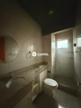 Foto interna de um banheiro com revestimento de azulejos brancos e pia.