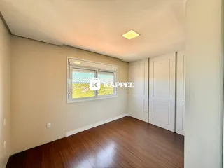 Uma sala com piso de madeira e uma janela que oferece uma vista externa.