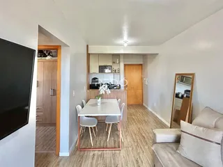 Ambiente de sala de jantar e cozinha em apartamento com piso de madeira clara.