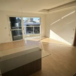 Uma sala de estar com piso de madeira e porta de vidro abrindo para o exterior.