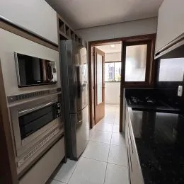 Foto interna de uma cozinha com armários e eletrodomésticos em um imóvel.