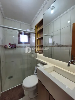 Foto de um banheiro com box de vidro e bancada branca.