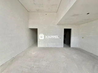 Foto de um espaço interno vazio com paredes de concreto e piso de cimento.