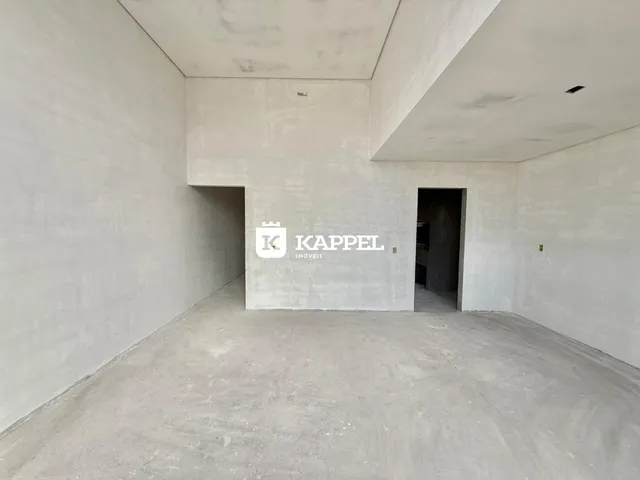 Foto de um espaço interno vazio com paredes de concreto e piso de cimento.