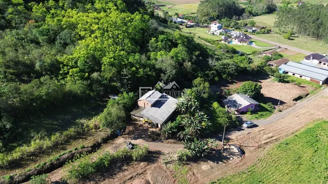 Vista aérea de uma propriedade rural com vegetação densa e estruturas no entorno.