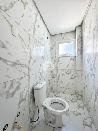Interior de um banheiro com revestimento de azulejos brancos e cinzas.