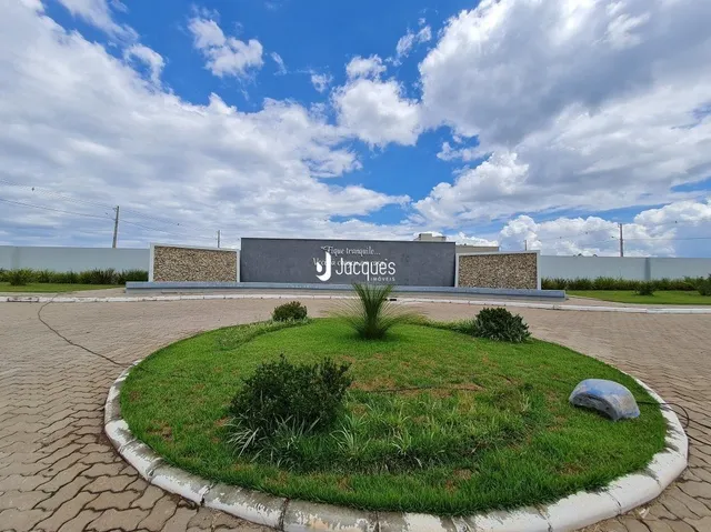 Vista externa de um terreno com gramado e muro de propriedade.