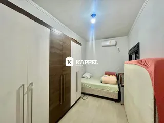 Quarto com cama e armários brancos em um ambiente claro.
