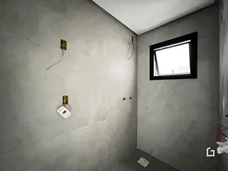 Parede interna com acabamento em concreto aparente e janela.