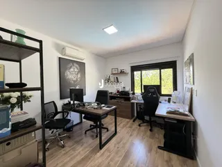 Ambiente de escritório com piso de madeira e grandes janelas em Lajeado.