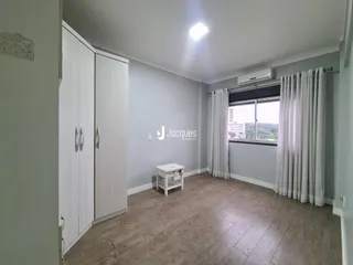 Quarto com armários brancos e piso de madeira clara em um imóvel no Brasil.