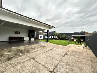 Foto da fachada de uma residência com área coberta e jardim.
