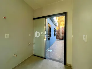 Hall de entrada com porta de vidro que dá acesso a uma área externa pavimentada.