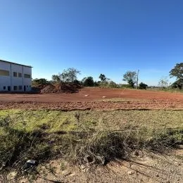 Vista de um terreno aberto com vegetação seca sob um céu azul.
