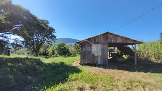 Estrutura rústica de madeira em um campo aberto sob o céu azul.