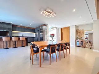 Sala de jantar com mesa de madeira e cozinha moderna em um imóvel no Brasil.