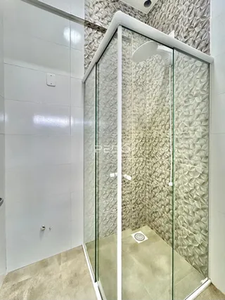 Interior de um box de banheiro com paredes texturizadas e vidro.