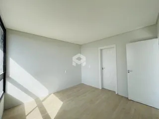 Vista interna de um cômodo com piso de madeira clara e paredes brancas.