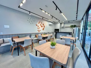 Uma sala de jantar moderna com mesas de madeira e cadeiras cinzas.