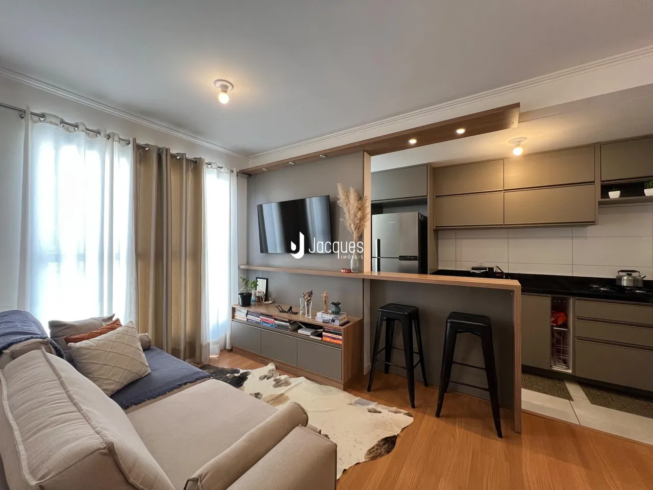 Sala de estar com piso de madeira e cozinha moderna em Lajeado.