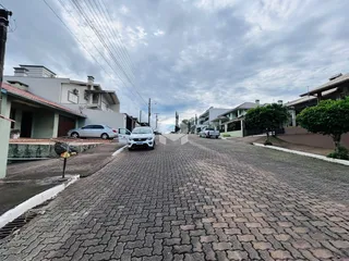 Vista da rua pavimentada em Lajeado, Brasil, com casas ao fundo.