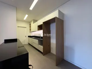 Interior de uma cozinha moderna com armários em madeira clara e bancada escura.