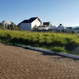 Foto da fachada de uma residência branca com vegetação no primeiro plano.