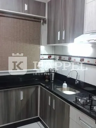 Uma cozinha moderna com armários superiores e inferiores e bancada escura.