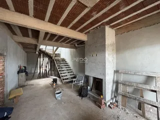 Espaço interno de construção com vigas expostas e paredes de tijolo.