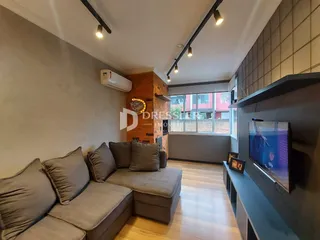 Sala de estar com sofá e piso de madeira em um imóvel no Brasil.