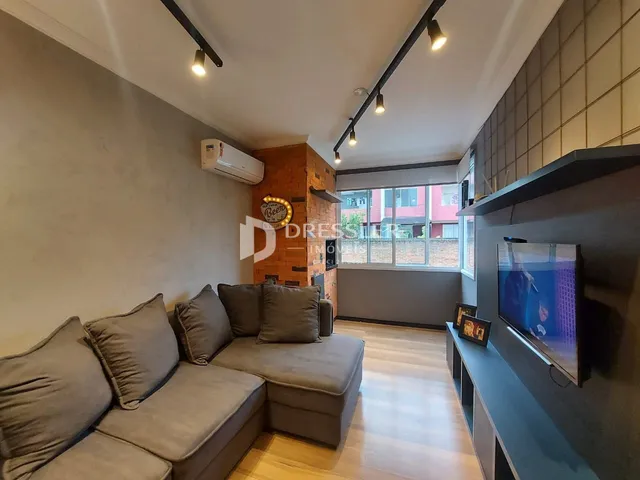 Sala de estar com sofá e piso de madeira em um imóvel no Brasil.
