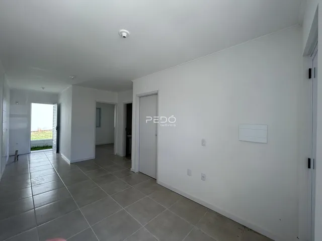 Hall de entrada com piso de cerâmica claro e paredes brancas.
