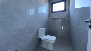 Foto de um banheiro com revestimento de azulejos brancos e vaso sanitário.